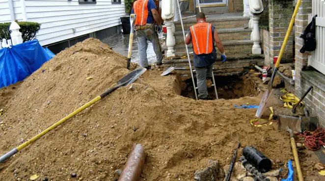 Contractors performing foundation protection and exterior drainage excavation near residential home steps in Knoxville, TN